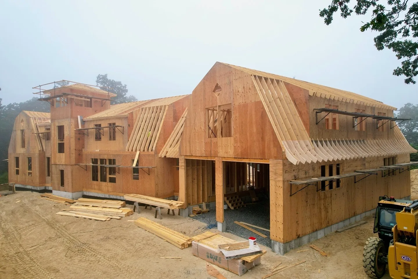 Wood framing of residential home in construction, showcasing roof trusses and scaffolding.