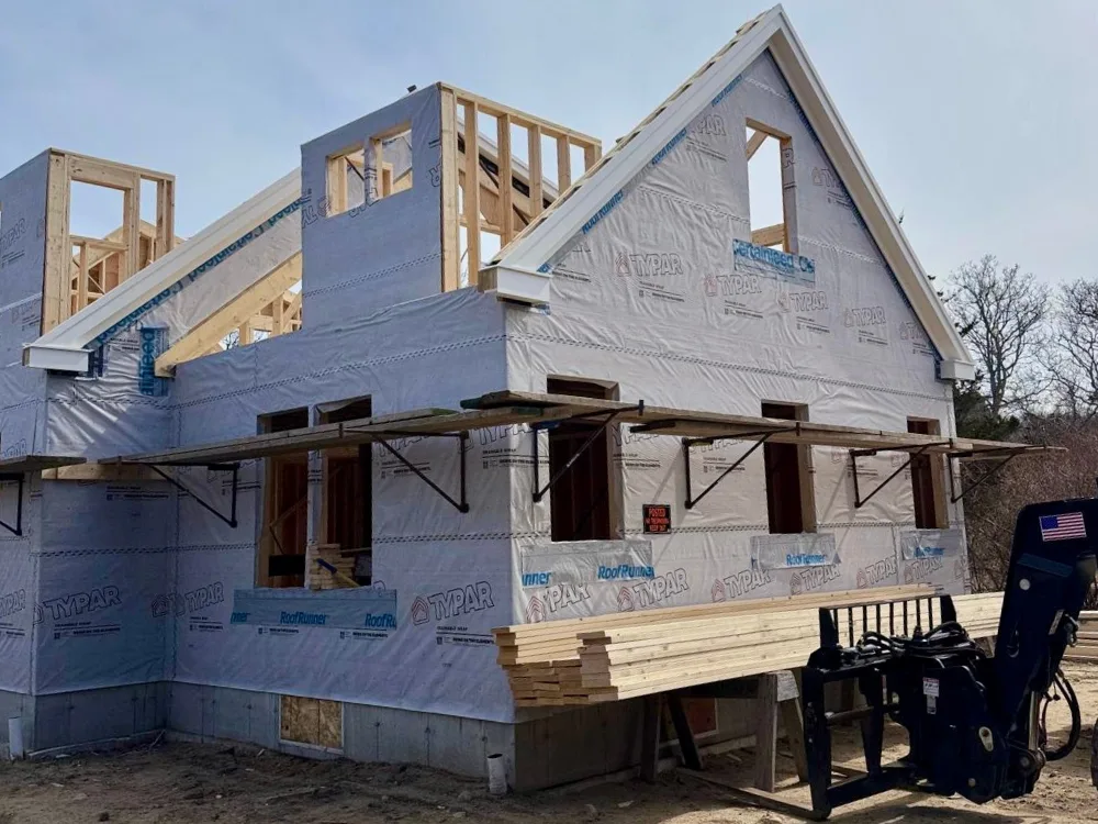 Residential construction framing showing the house structure and roof preparation in progress.